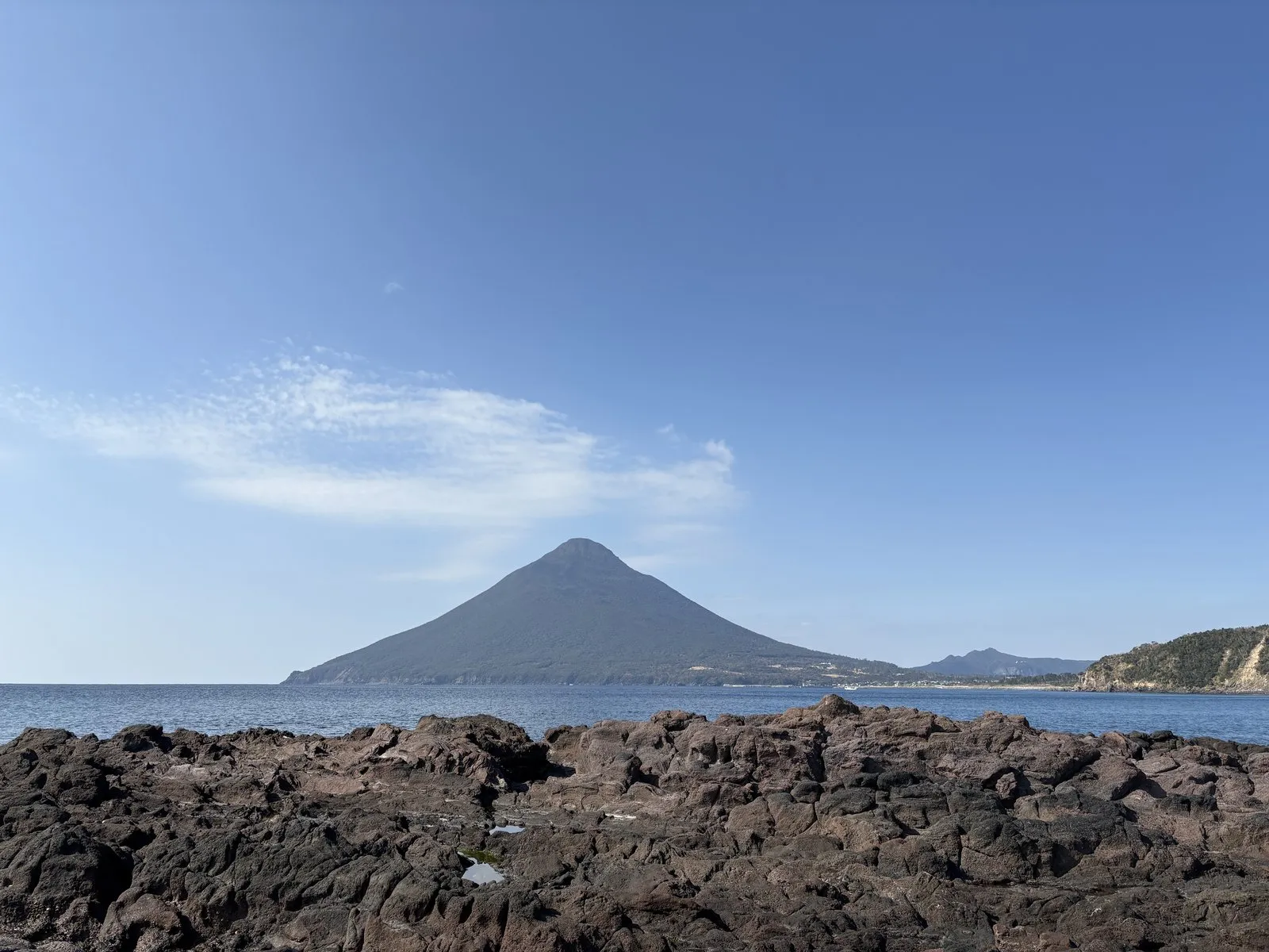 長崎鼻の黒い溶岩の磯の向こうに、三角形の開聞岳がそびえる