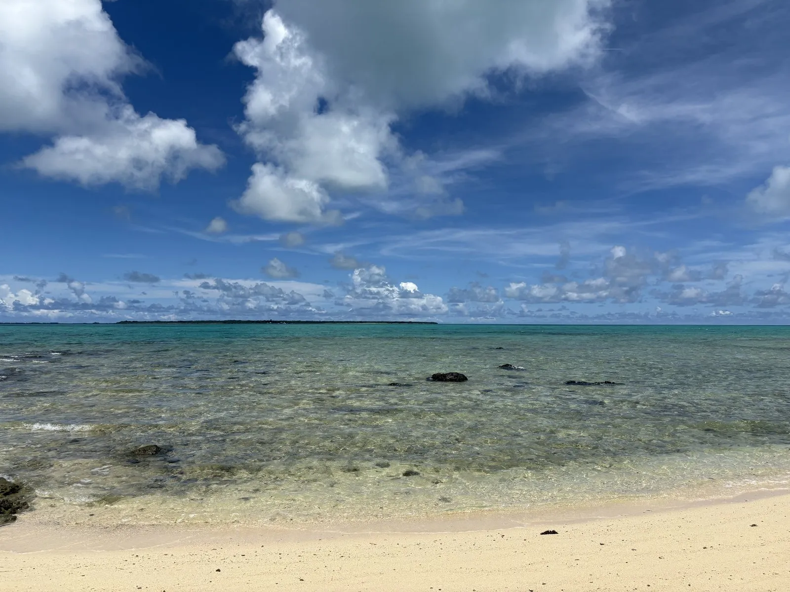 浜島周辺の白い砂浜と透き通った浅瀬。黒い岩がところどころに点在する