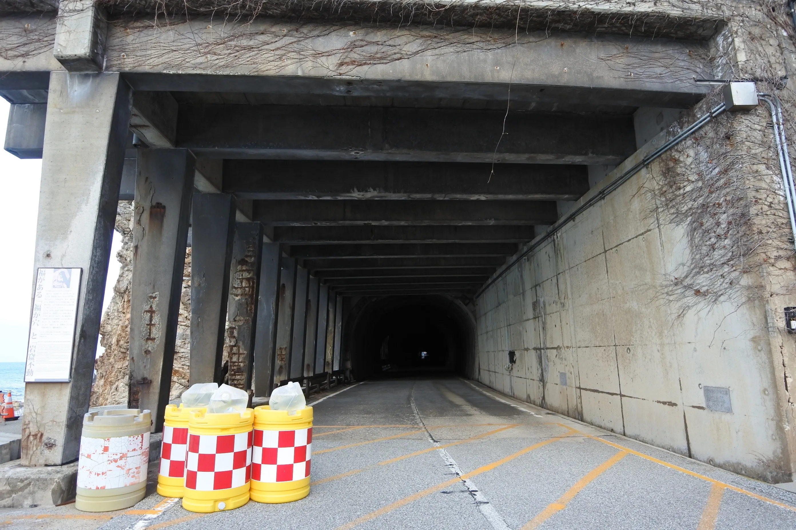 海沿いの古い素掘りトンネル。岩の合間から夕暮れの海が覗く