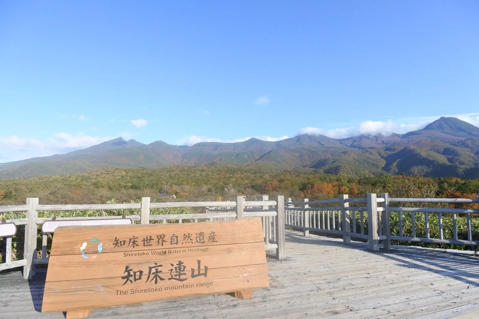 知床五湖の高架木道。「知床世界自然遺産／知床連山 The Shiretoko mountain range」の木製看板と、その奥に連なる知床連山